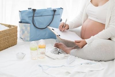 Future maman réalisant une liste de naissance sur un calepin.